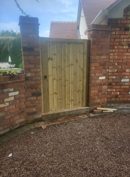 Solid timber garden gate fitted between brick pillars